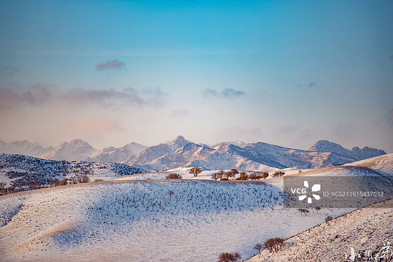 雪落群山，将起伏的丘陵与远处的峰峦都化作银白的诗行，稀疏的林木在雪色中凝成剪影，拍摄：辽宁盘锦~图片素材