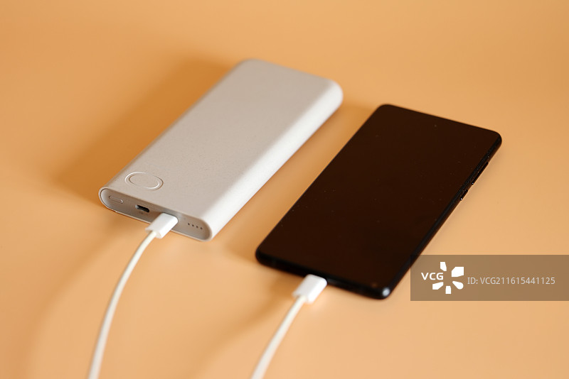 橙色背景下的智能手机和移动电源充电宝数据线特写镜头图片素材