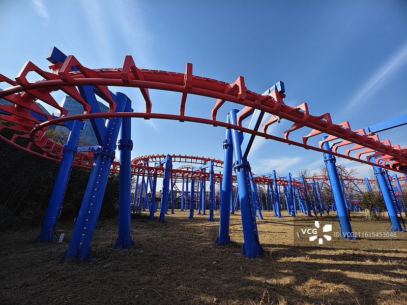 游乐园过山车：红蓝轨道架构与蓝天，动感游乐设施的视觉冲击图片素材