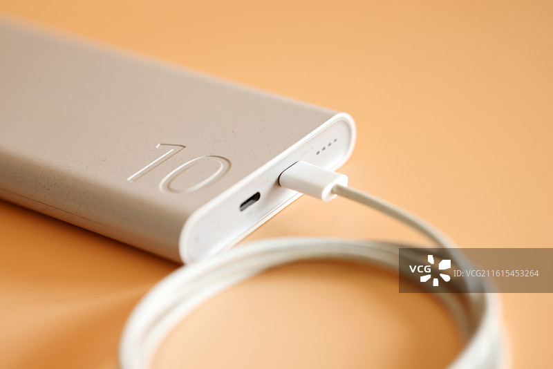 橙色背景下的智能手机和移动电源充电宝数据线特写镜头图片素材