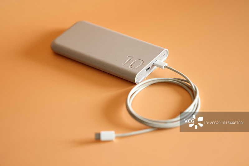 橙色背景下的智能手机和移动电源充电宝数据线特写镜头图片素材