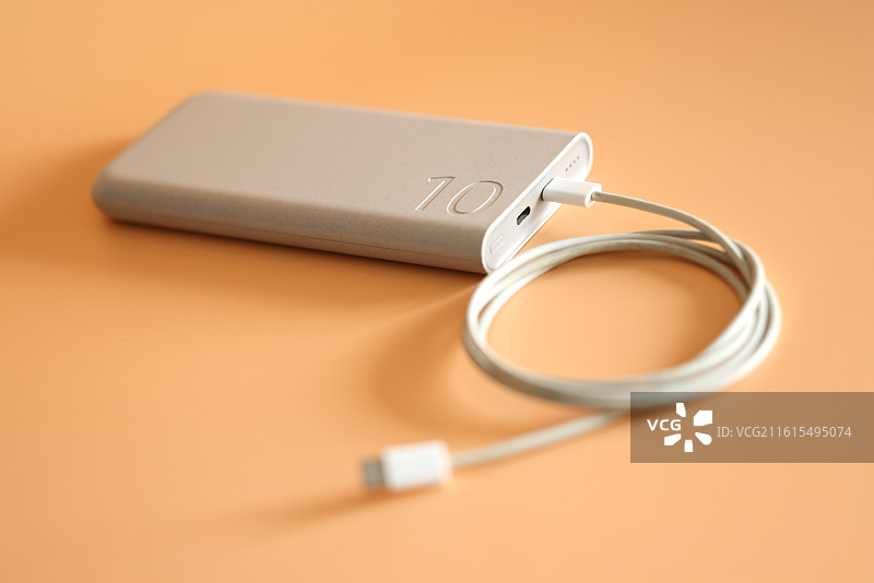 橙色背景下的智能手机和移动电源充电宝数据线特写镜头图片素材