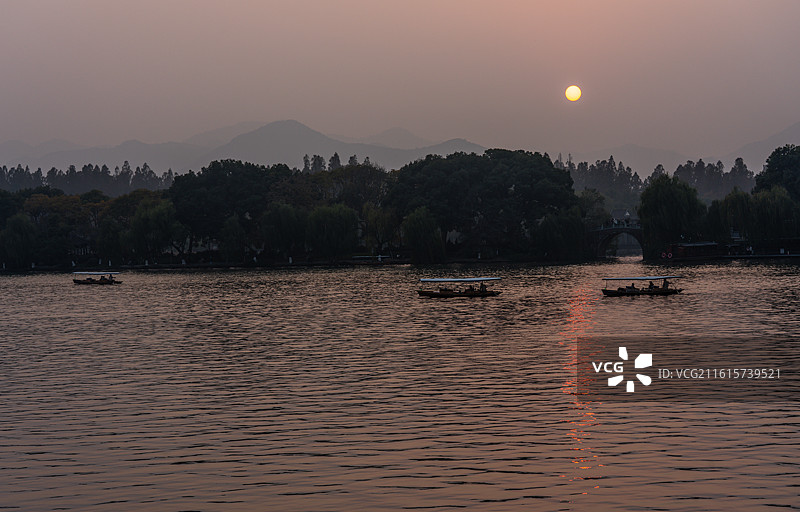 浙江杭州西湖孤山路口西泠桥看黄昏夕阳日落中的山水自然景观与游船图片素材