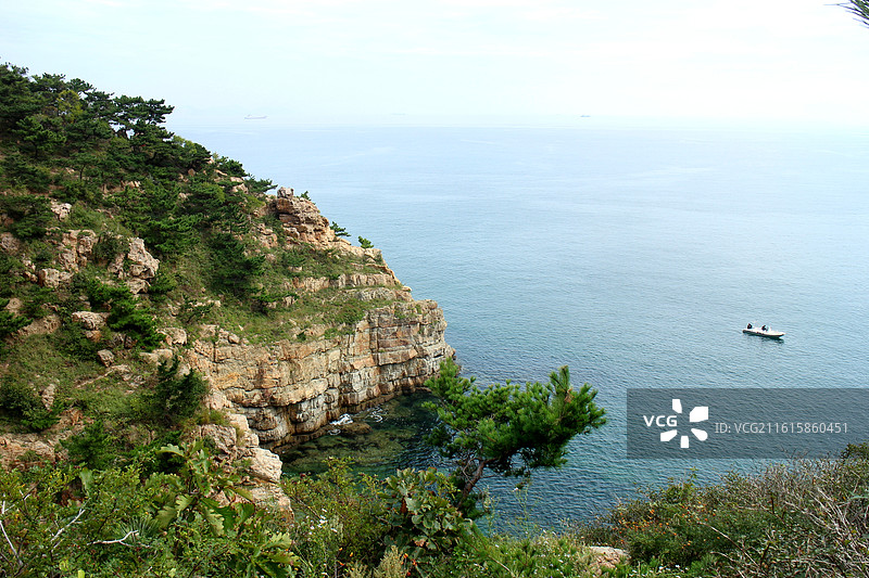 站在大连海之韵公园的旭日广场附近，看到连绵的群山沿着海岸线延伸，山上植被茂密，郁郁葱葱。图片素材