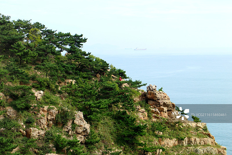 站在大连海之韵公园的旭日广场附近，看到连绵的群山沿着海岸线延伸，山上植被茂密，郁郁葱葱。图片素材
