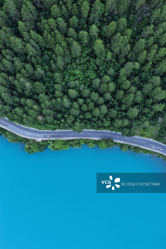九寨沟犀牛海环湖公路航拍，上半部分是茂密的森林，下半部分是犀牛海标志性的高饱和度碧蓝色湖面。图片素材