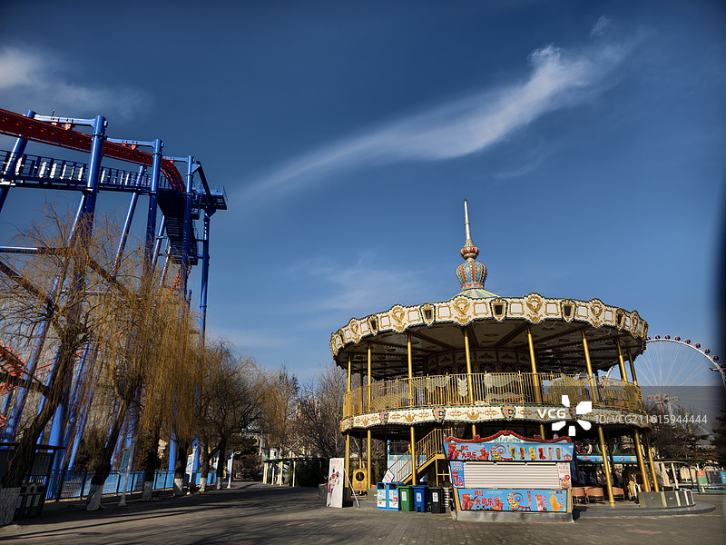 游乐园旋转木马：金色装饰与过山车，经典游乐设施的童话氛围图片素材