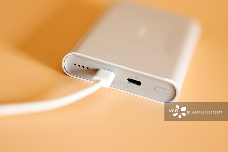 橙色背景下的智能手机和移动电源充电宝数据线特写镜头图片素材