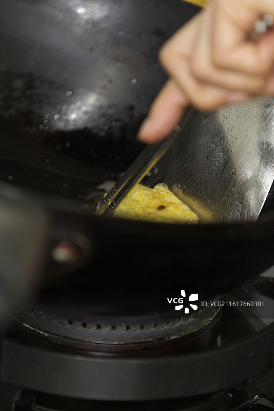 黑色铁锅食物油中正在煎炸的金黄美味蛋饺家常菜特写镜头图片素材