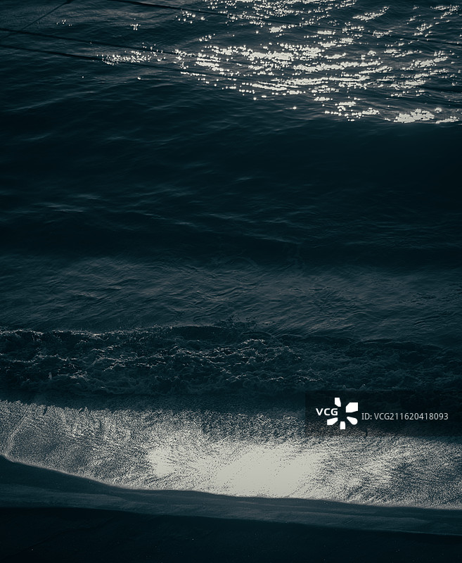 日本伊豆海岸，水面捕捉金色阳光反射，黑白对比展现海洋的神秘魅力。图片素材