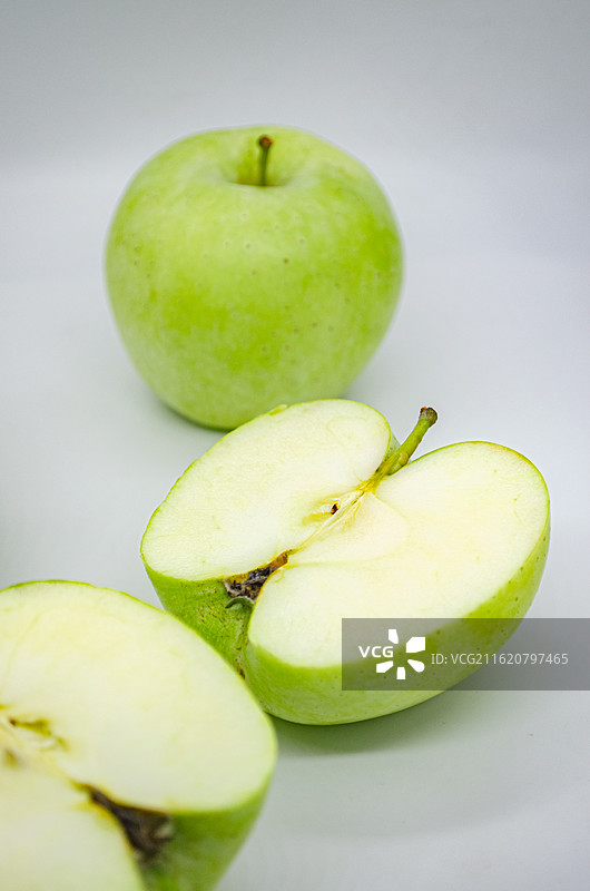 中国传统水果美食饮食产业影棚拍摄主题，白色背景下切开的翠绿色黄色的青苹果，室内无人图像摄影图片素材