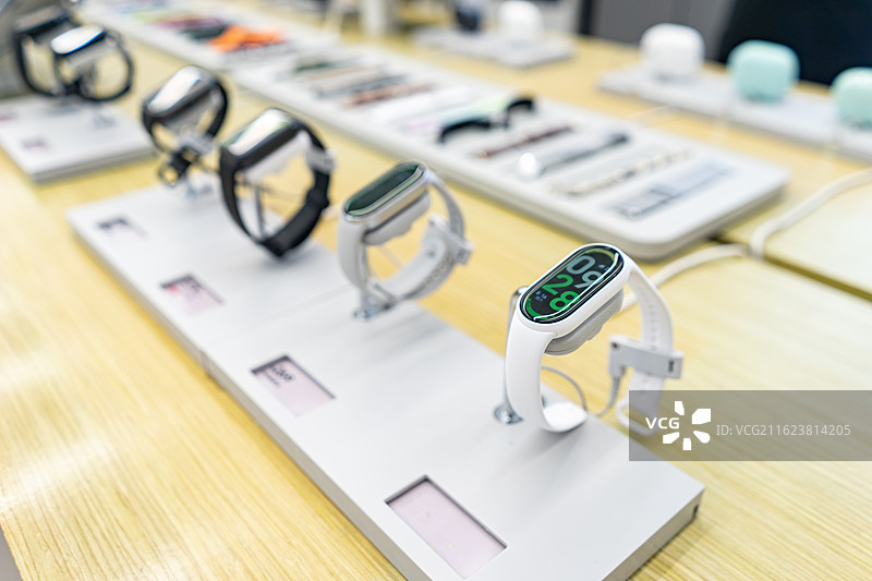 中国电子产品拍摄主题，专卖店的桌子上摆放着成一排的运动智能手表腕表手环，室内无人图像摄影图片素材
