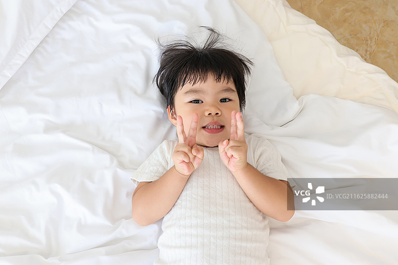 床上可爱小孩比耶图片素材