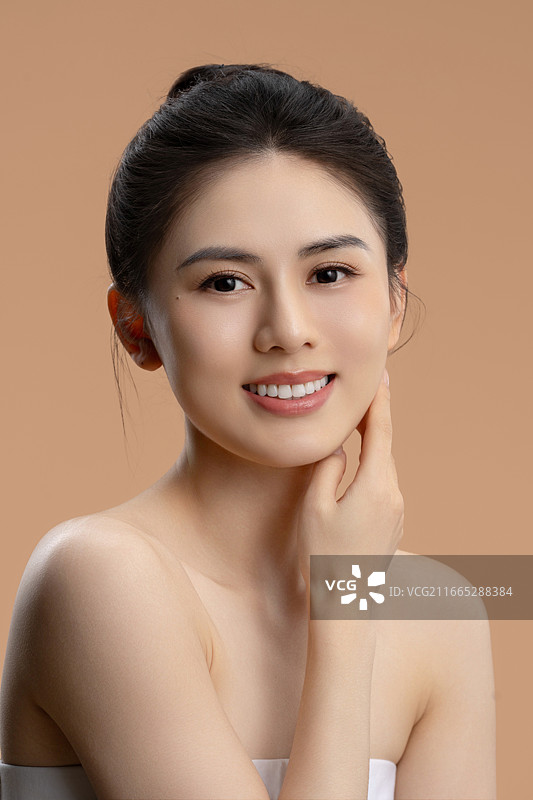 年轻亚洲女性手托脸颊微笑的护肤美妆肖像图片素材