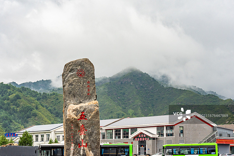 雨后山西五台山游客中心，红色 “五台山”刻字景观石立于广场，地面积水映出倒影，远山云雾缥缈图片素材