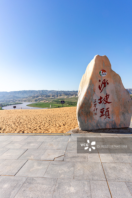 宁夏中卫沙坡头景区标志性景观石，巨石上镌刻红色 “沙坡头” 大字,石碑立于观景平台，背景沙漠与黄河图片素材