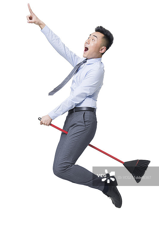 年轻商务男士骑着扫帚飞行图片素材