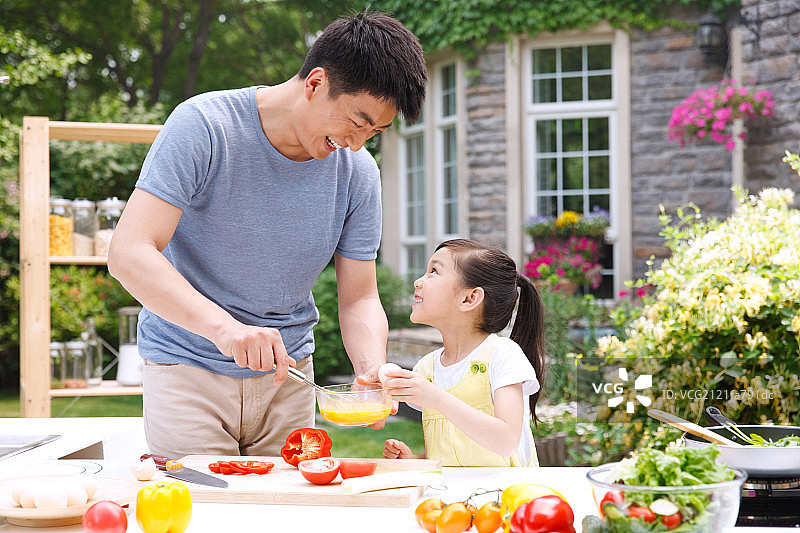 父亲和女儿在户外厨房准备食物图片素材