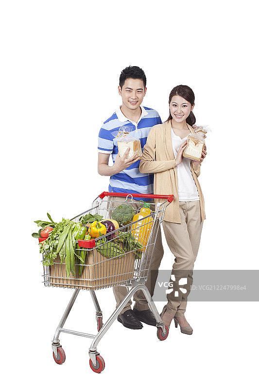 一对青年男女手拿面包和一辆装满蔬菜的购物车图片素材