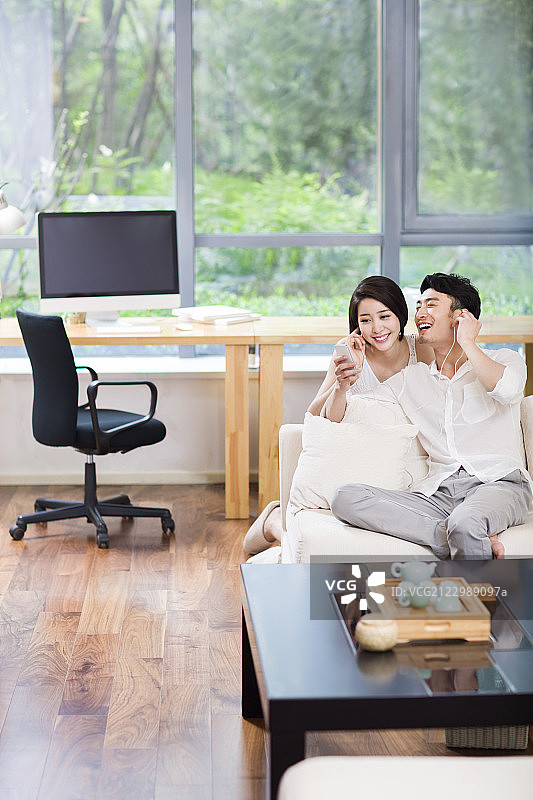 快乐的年轻情侣在家听音乐图片素材