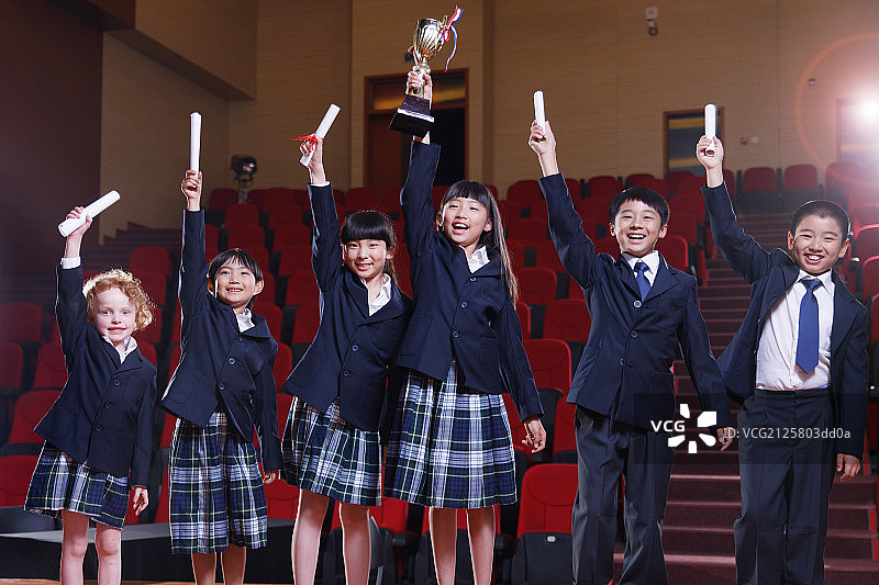 小学生拿着奖品在礼堂里图片素材