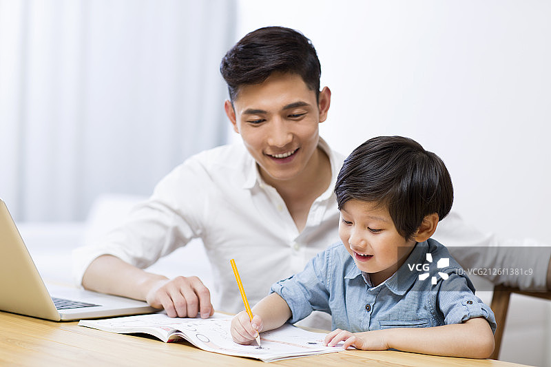 父亲指导男孩做家庭作业图片素材