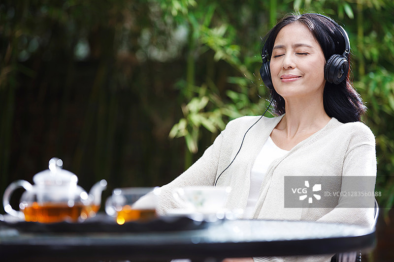 中年女人坐在椅子上戴着耳机图片素材