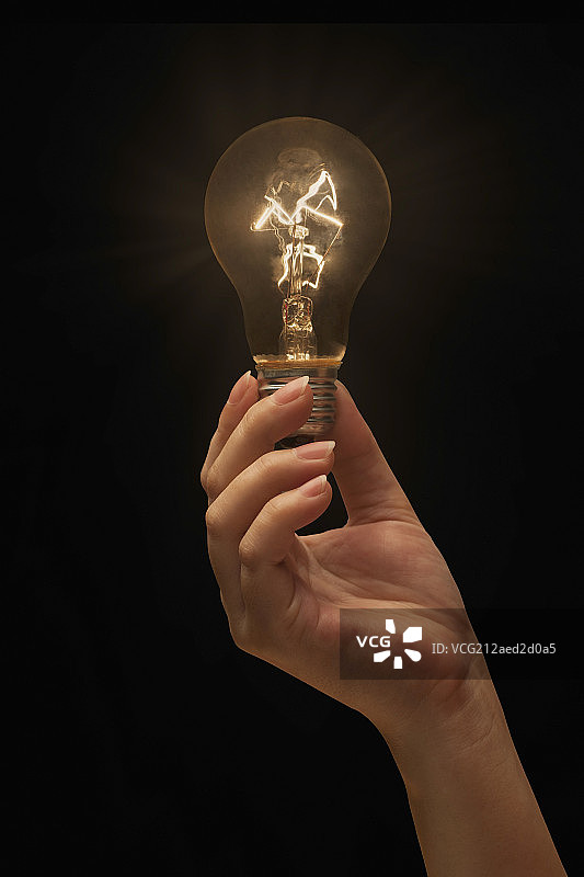 女人的手拿着点亮的灯泡图片素材