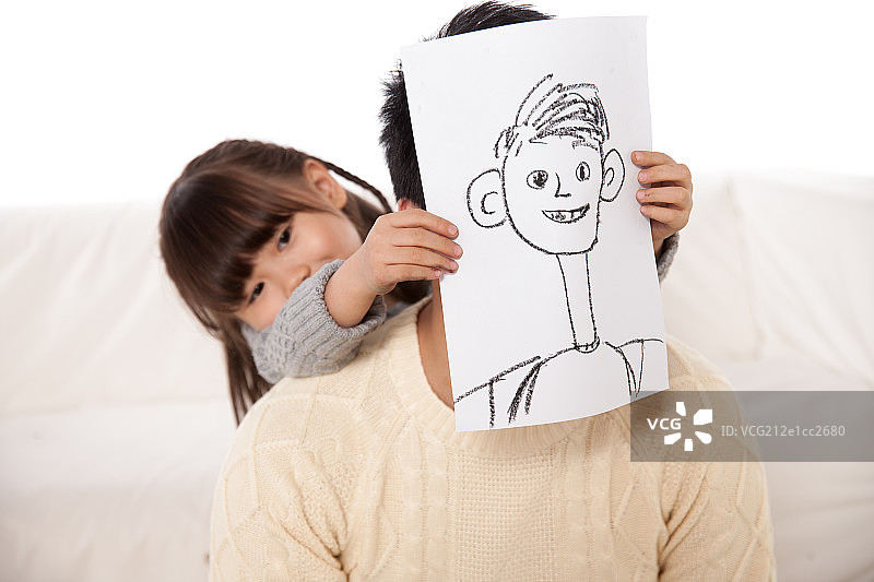女儿拿着绘画作品遮盖在父亲脸色图片素材