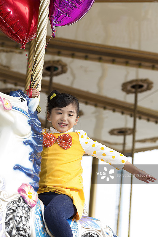 小女孩在游乐园骑旋转木马图片素材