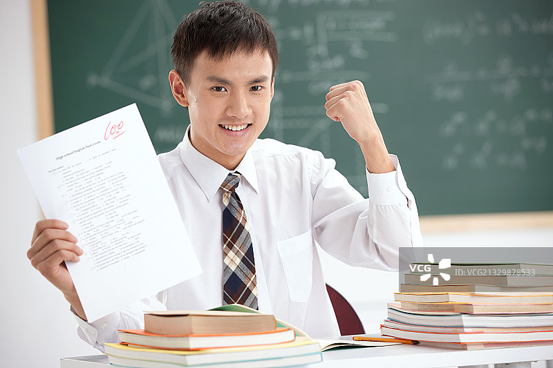 一个中学男生展示试卷在教室里图片素材
