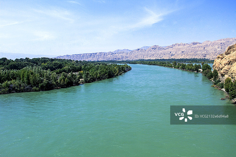 蓝色的黄河树林和远处的沙山图片素材