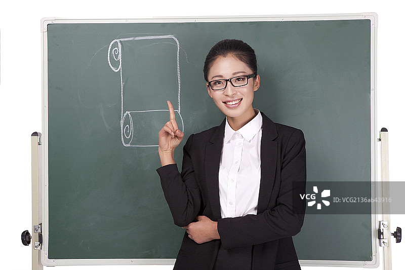 一个做着手势的青年女教师和粉笔画图片素材