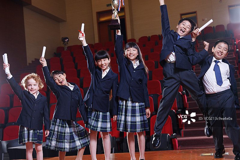 小学生拿着奖品在礼堂里图片素材
