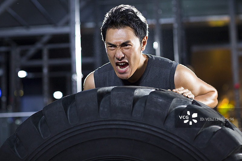 年轻男子在健身房做翻轮胎训练图片素材