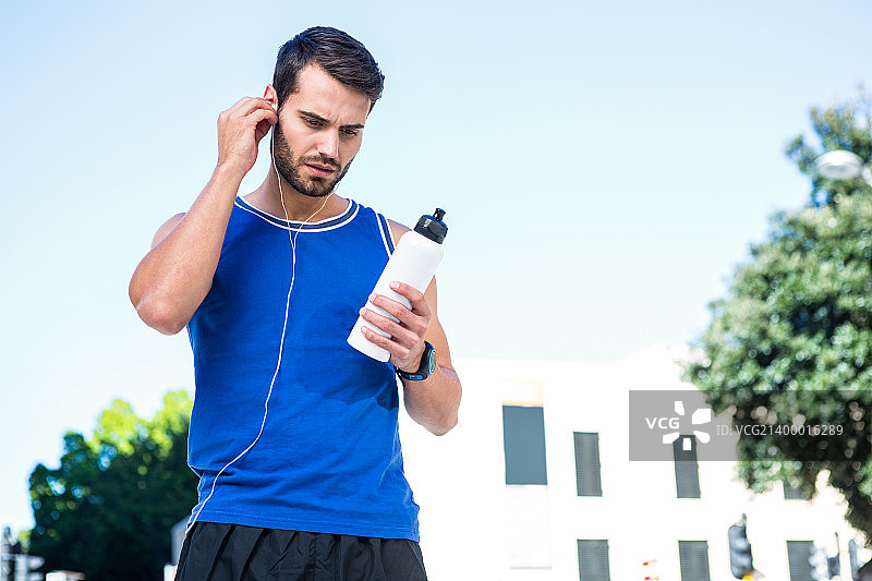 在城市里看着瓶子的英俊运动员图片素材