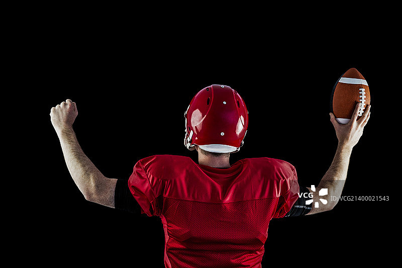 美式橄榄球运动员在黑色背景下凯旋的背影图片素材