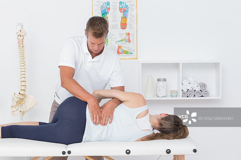 在医疗办公室内，医生检查男人的背部图片素材