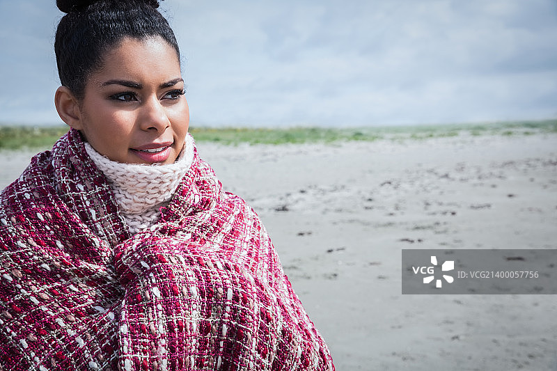 在海滩上裹着暖和衣服的漂亮女人图片素材