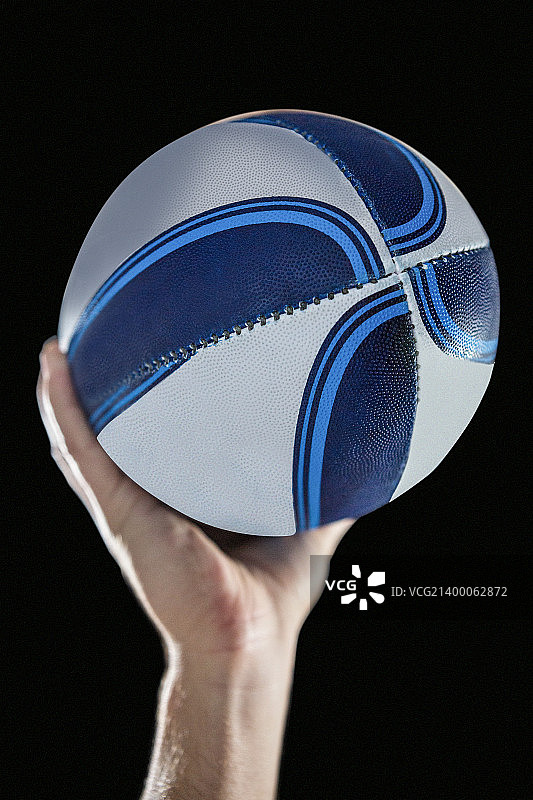 橄榄球运动员举起手臂持球的特写（黑色背景）图片素材