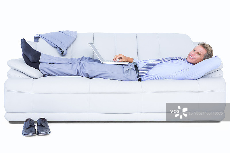 商人躺在沙发上使用图片素材