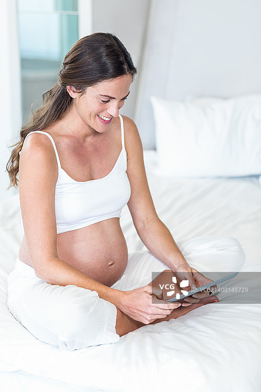 快乐的孕妇使用数码设备图片素材