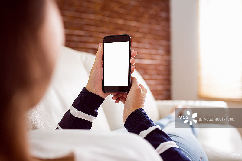 亚洲女人在沙发上使用手机图片素材