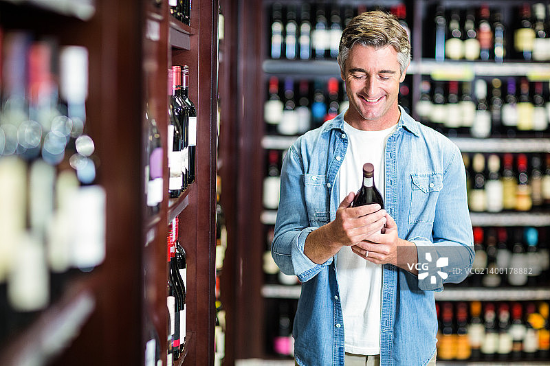 微笑的男人拿着一瓶葡萄酒图片素材