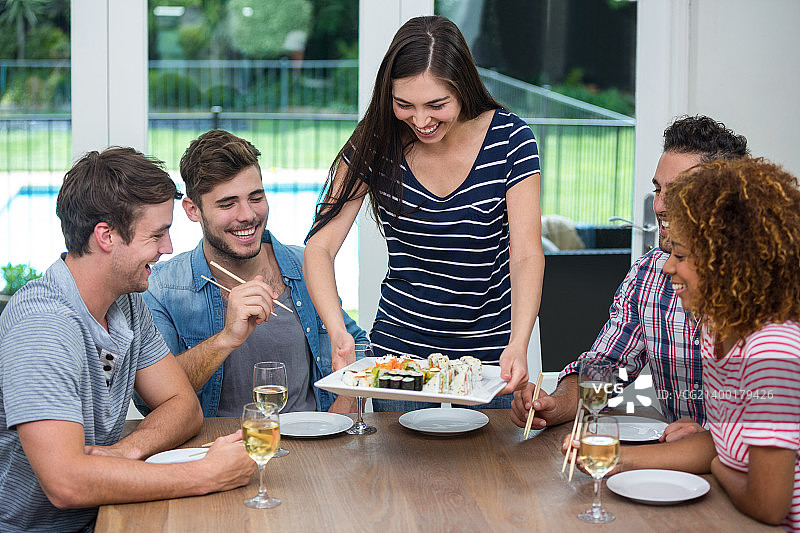 快乐的年轻女子端寿司图片素材