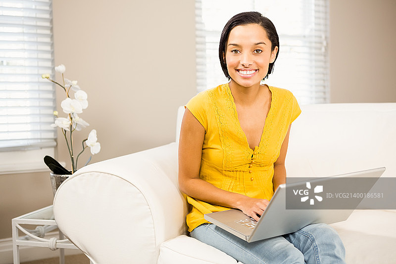 微笑的棕发女子在笔记本电脑上使用笔记本电脑图片素材