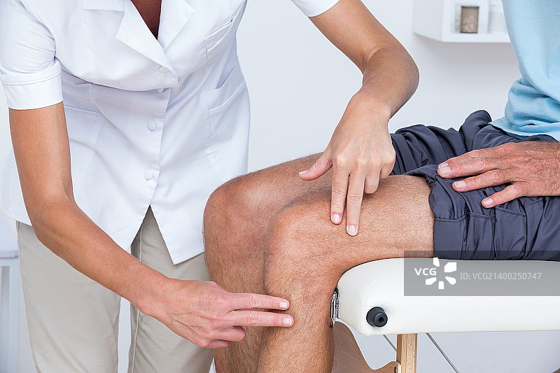 医生在医务室检查病人的膝盖图片素材