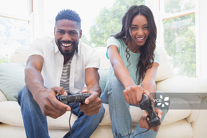 在客厅沙发上玩电子游戏的快乐情侣图片素材