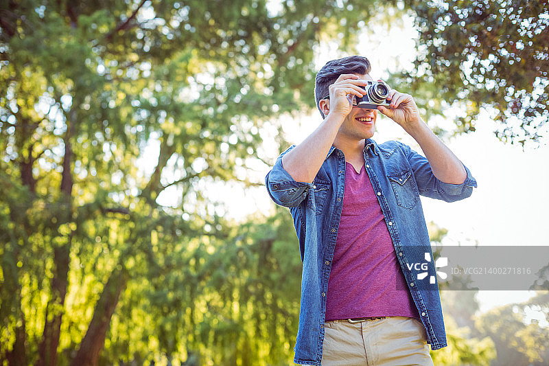 阳光明媚的日子里使用复古相机的英俊男人图片素材