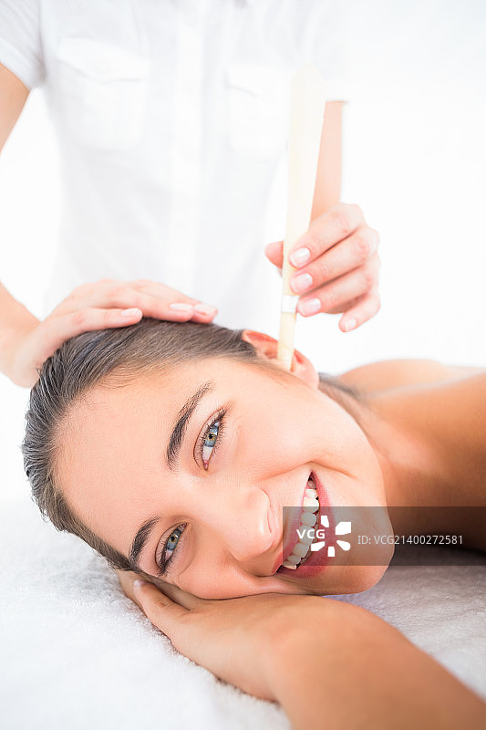 年轻女子在水疗中心接受耳烛护理的侧面照图片素材